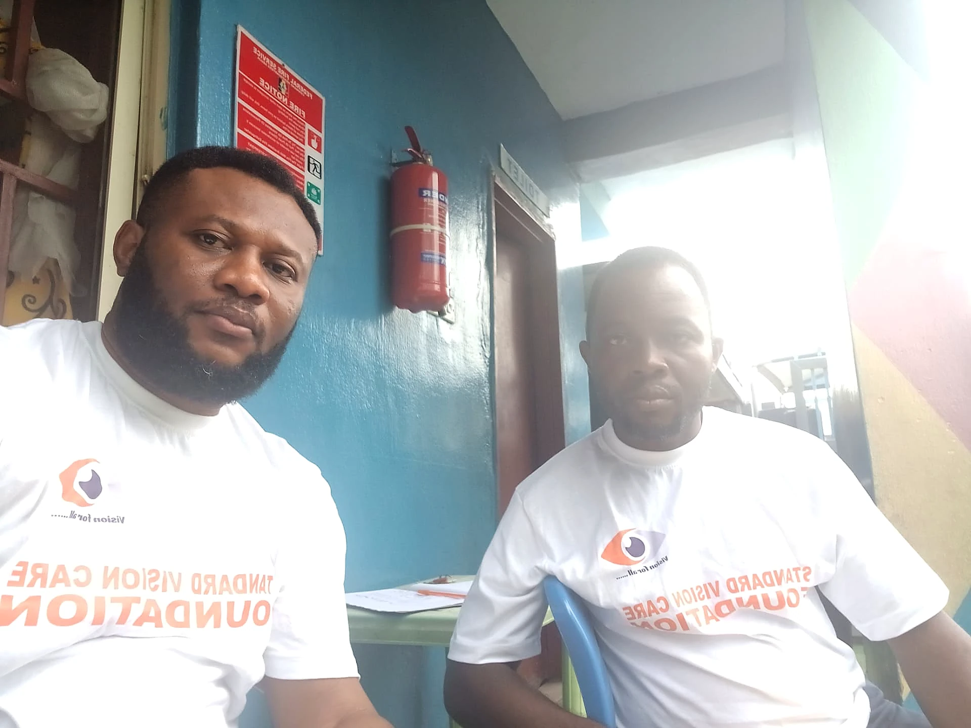 Two Standard Vision Care Foundation team members wearing their Foundation outreach shirts at Amazing Stars International Academy