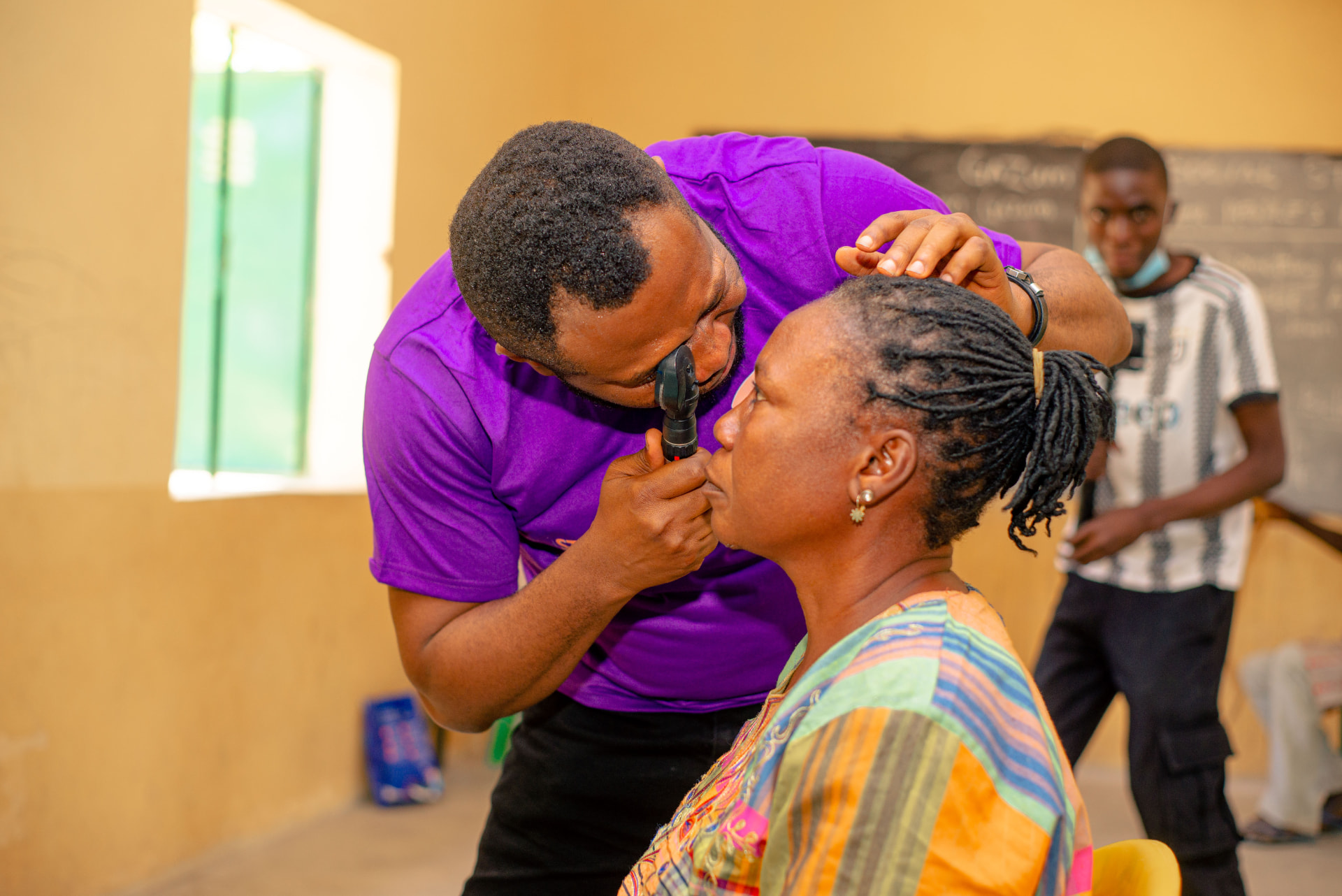 Foundation optometrist examining a woman's eyes with a direct ophthalmoscope